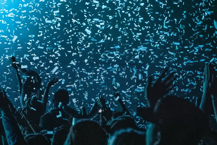 Confetti falling over a crowd celebrating under a blue light