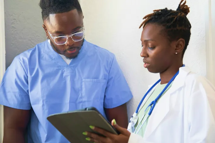 Two doctors talking while looking at a clipboard