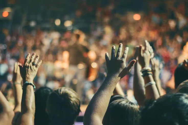 A view of a crowd at an event with their hands in the air