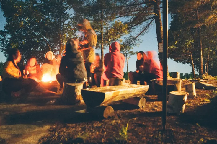 People sat around a campfire at dusk