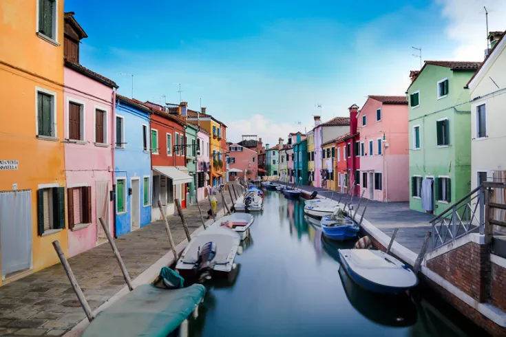 Colourful buildings alongside a canal with boats.