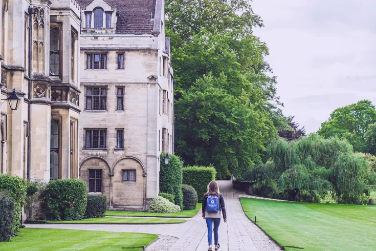 A student walking past historic university buildings.