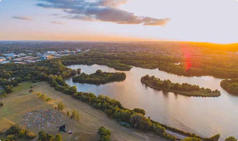 A view from high up of countryside water ways and lake next to a town, at sunset.