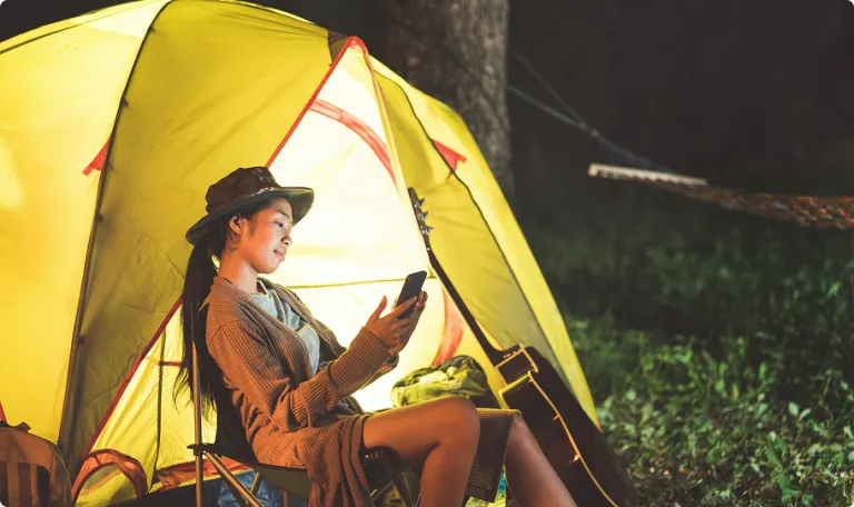 Woman sitting outside a tent at night time