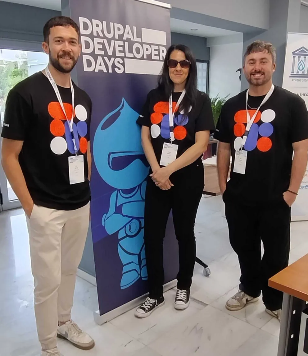 Three Zoocha team members posing beside a Drupal Developer Days Athens 2026 banner
