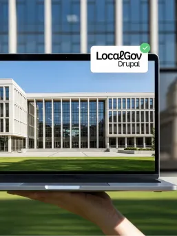 A hand holding a laptop in front of a government building