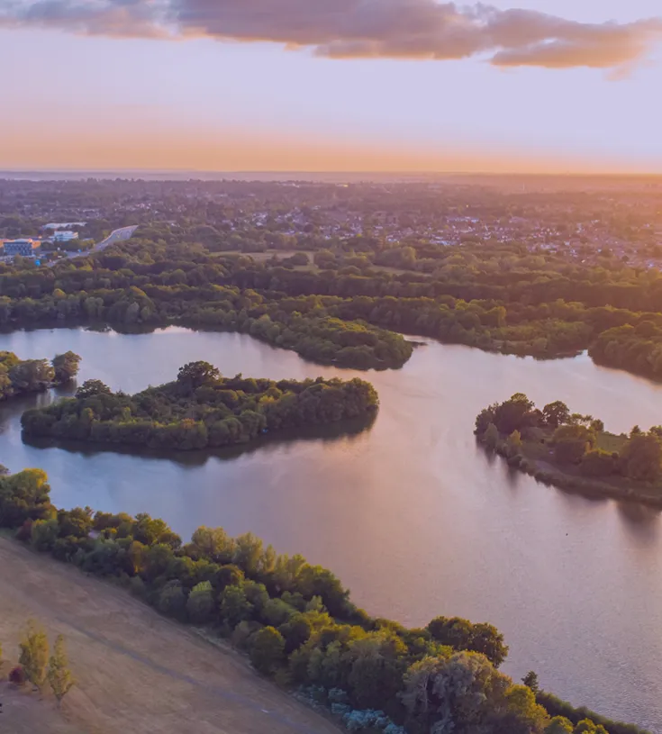 Image of a view from high up over a beautiful lake next to a town at sunset