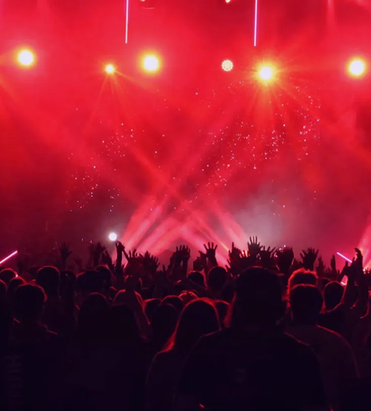 Image of a dark stage and people watching with red lights