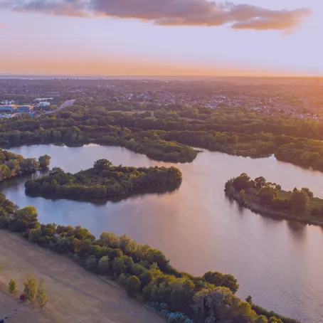 A view from high up over a beautiful lake next to a town at sunset