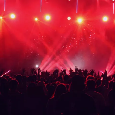 Image of a dark stage and people watching with red lights