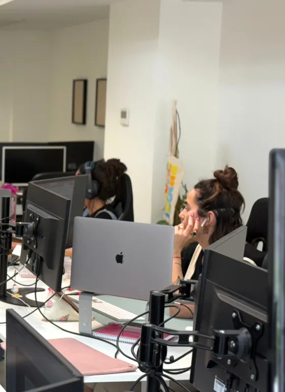 Open plan desk with computers and a person working
