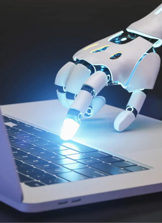 A robotic hand pressing glowing keys on a laptop
